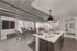 Chic modern apartment interior with open-plan layout featuring a sleek kitchen island, dining area, and cozy living space under industrial-style ceilings.