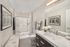 Bright and modern bathroom featuring a sleek glass shower, elegant vanity with fresh flowers, and contemporary decor.