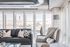 Bright and modern living room with large windows, featuring a sleek black sofa, elegant armchair, and stylish decor.