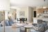 Bright and inviting open-concept living area featuring modern decor, a cozy seating arrangement, and a stylish kitchen with wooden cabinetry.