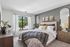 Elegant bedroom with large window, plush decor, neutral tones, and stylish artwork creating a serene atmosphere.