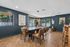 Elegant dining area with a modern dark table, stylish leather chairs, and chic contemporary art on deep blue walls.