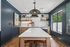 Modern kitchen with sleek pendant lights, elegant wooden cabinetry, and a chic marble island, offering a perfect blend of style and functionality.