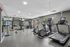 Modern fitness center with state-of-the-art equipment including treadmills, ellipticals, and strength training machines in a bright, spacious setting.