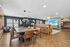 Modern open-concept living space featuring elegant dining area with leather chairs, cozy lounge with plush seating, and stylish wooden flooring.