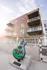 Contemporary apartment building exterior with stylish balconies and a vibrant guitar sculpture, set against a clear sky.