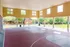 Spacious indoor basketball court with sunlit open walls and a view of lush greenery.