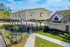 Elevated modern architecture with arched supports above a basketball court, surrounded by lush greenery and elegant fencing.