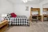 Cozy bedroom with stylish checkered bedding, modern wooden desk, and warm lighting, perfect for relaxation and productivity.