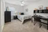 Cozy bedroom with plush carpeting, modern furniture, and a stylish desk; perfect for comfort and productivity.