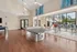 Modern recreation area with a sleek ping pong table, stylish high chairs, and large windows overlooking a sunny patio with poolside loungers.