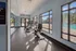 Bright and airy gym room with modern exercise equipment and large windows overlooking a sparkling outdoor pool.
