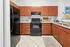 Modern kitchen with sleek black appliances, rich wooden cabinetry, and granite countertops for an elegant cooking space.