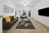 Modern living room with sleek gray sofas, vibrant orange pillows, contemporary wall art, and a stylish glass coffee table on a patterned rug, creating a welcoming and chic atmosphere.