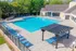 Inviting outdoor pool area with ample seating, shaded pergola, and lush green surroundings, perfect for relaxation and leisure.
