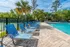 Inviting swimming pool area with stylish blue lounge chairs, surrounded by lush green trees and a bright blue sky.