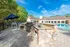 Elegant outdoor patio featuring a stylish barbecue grill and seating area adjacent to a sparkling swimming pool with lush greenery.