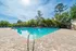 Inviting outdoor pool surrounded by lush greenery and sun loungers, perfect for relaxation and leisure.