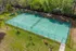 Lush green tennis court surrounded by trees, perfect for outdoor recreation and community sports.