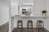 Modern kitchen with sleek granite countertops and stylish bar stools, featuring stainless steel appliances and bright white cabinetry, creating an inviting culinary space.