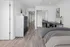 Modern bedroom with sleek wooden floors, a contemporary dresser, and a stylish workspace featuring a dual desk setup and sophisticated wall art.