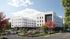 Contemporary apartment complex with sleek architectural design, surrounded by lush green landscaping and vibrant trees, featuring ample parking and serene outdoor spaces.