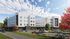 Modern apartment complex surrounded by lush greenery and colorful autumn trees under a vibrant blue sky.