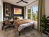 Chic bedroom with a cozy bed, stylish desk, and a leafy view through large windows. Modern decor with vibrant wall art and lush greenery.