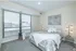 Cozy bedroom with large windows, modern decor, and a comfortable bed.