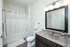 Modern bathroom with sleek fixtures, large mirror, and a white shower curtain.