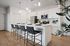 2-Bedroom Apartments in East Mesa, AZ - Acero Eastmark - Modern White Kitchen Featuring Island Seating, Pendant Lights, Stainless Steel Appliances, and Wood-Style Flooring.