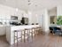 Pet-Friendly Apartments in Glendale AZ - Acero at the Stadium - Modern Kitchen with White Cabinetry, Stainless Steel Appliances, Large Island with Seating, White Countertops, and Hanging Light Set Up