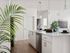 Two-Bedroom Apartments in Glendale, AZ - Acero at the Stadium - Bright White Kitchen With Large Quartz Island, Undermount Sink, Pendant Lights, and Stainless Steel Dishwasher In Open Layout.