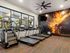 Apartments for Rent in Glendale, AZ - Acero at the Stadium - Fitness Center with Carpeting, Treadmills, an Elliptical, a Ceiling Fan, Large Windows, and a Wall-Mounted TV.