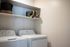Three-Bedroom Apartments in Glendale, AZ - Acero at the Stadium - In-Home Laundry Room With Full-Size Washer and Dryer, Wall Shelving, and Storage Baskets In Clean Neutral Space.