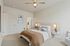 Three-Bedroom Apartments in Vancouver, WA - Bennington on First - Bedroom with Carpeted Floor, Bed, Floating Nighstands with Lamps, Ceiling Fan, and Ensuite Bathroom