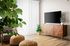 Eastmark, AZ, Pet-Friendly Luxury Apartments - Acero Hawes Crossing - Bright Living Room With Wood Style Flooring, Vertical Blinds, Mid Century Media Console, And Potted Plants.