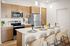 Luxury Apartments in Mesa, AZ - Acero Hawes Crossing - Kitchen with Quartz Countertops, Stainless Steel Appliances, Kitchen Island, and Vinyl Plank Flooring.