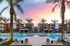 Apartments In Goodyear For Rent - Acero Roosevelt - A Large Resort-Style Pool With Water Features Surrounded By Lounge Seating And Palm Trees