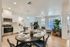 Three-BR Apartments in West Phoenix, AZ - Meritum Sheely Farms - Kitchen with Vinyl Plank Flooring, Quartz Counters, Stainless Steel Appliances, White Cabinets, a Kitchen Island, Modern Light Fixtures, a Ceiling Fan, the Living Room, and Stylish Decor