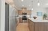 Vancouver, WA Dog-Friendly Apartments - Acero Jensen Park - MOdern Kitchen with Wood-Style Cabinetry, Stainless Steel Appliances, White Countertops, and Large Cooking Island