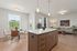 Apartments in Vancouver, WA - Acero Jensen Park - An Open-Concept Apartment Interior with a Kitchen Island, Pendant Lighting, Dining Area, Living Area, and Wood-Style Flooring.