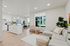 Apartments for Rent in Vancouver, WA - Bennington on First - Open Concept Living Room with Vinyl Plank Flooring, Area Rug, Sectional Couch, Ottoman, Chair, Spacious Windows, Air Conditioning Unit, and View of Kitchen and Dining Area