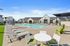 2 BR Apartments In Vancouver, WA - Bennington on First - Sparkling Swimming Pool With Lounge Chairs, Tables, Grass Area, And Umbrellas