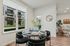 Vancouver, WA, Columbia Tech Center Apartments - Bennington on First - A Dining Area with a Round Table Set for Four, Upholstered Chairs, Table Décor, a Large Window, Wood-Style Flooring.