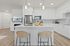 3-Bedroom Apartments in Camas, WA - Bennington on First - Spacious White Kitchen With Oversized Quartz Island, Pendant Lights, Stainless Steel Appliances, And Wood Style Flooring.