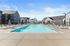 Vancouver Apartments for Rent - Bennington on First - A Swimming Pool Surrounded by Lounge Chairs, Umbrellas, Fencing, and Modern Residential Buildings.