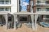 2-Bedroom Luxury Apartments in Eastmark, AZ - Acero Hawes Crossing - Poolside Cabanas With Draped Curtains, Outdoor Lounge Seating, And Mounted TVs Framed By Modern Apartment Buildings.