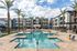 Apartments for Rent in East Mesa, CA - Acero Hawes Crossing - Swimming Pool with Lounge, Tanning Chairs, Umbrellas, Chairs, Tables, Palm Trees, and Access to BBQ Area.