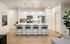 1 BR Apartments in West Phoenix, AZ - Meritum Sheely Farms - Kitchen With Vinyl Plank Flooring, Quartz Counters, Stainless Steel Appliances, White Cabinets, Kitchen Island, Modern Light Fixtures, Ceiling Fan, And Stylish Decor